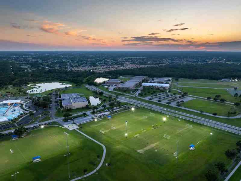 Aerial view of public sports park with people engaged in football game