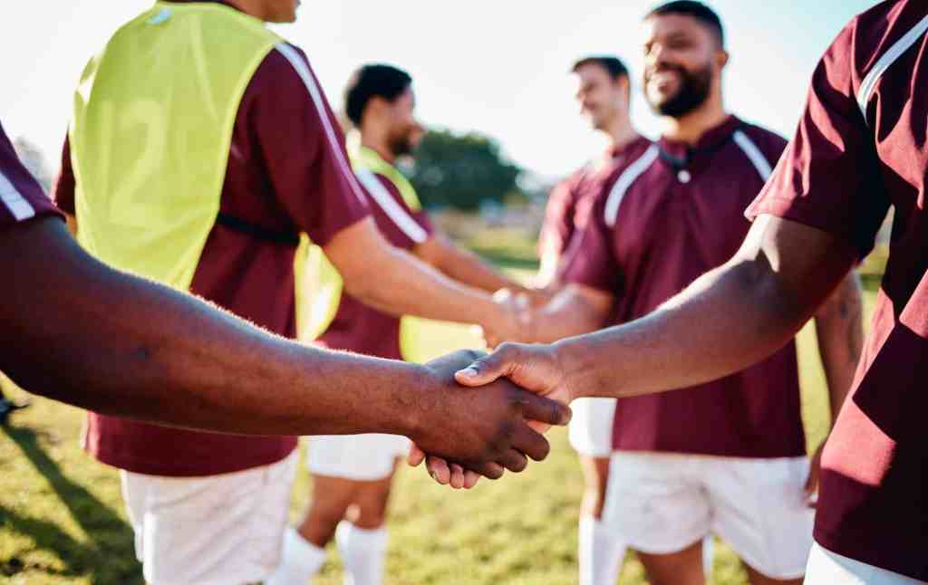 Men, sports and handshake for greeting, introduction or sportsmanship on the grass field outdoors.