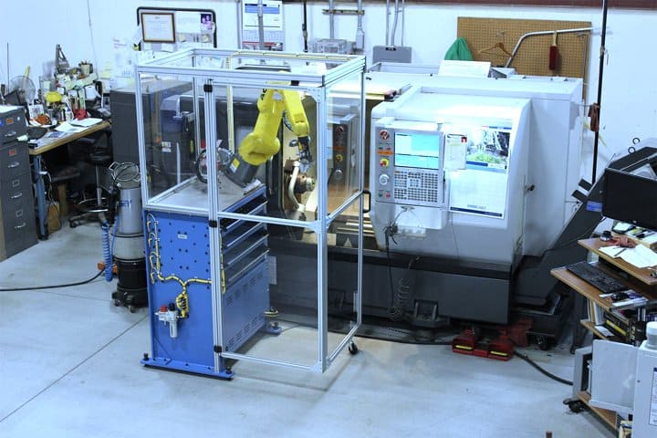 Automated manufacturing robot inside a protective enclosure at Adaptec Solutions.