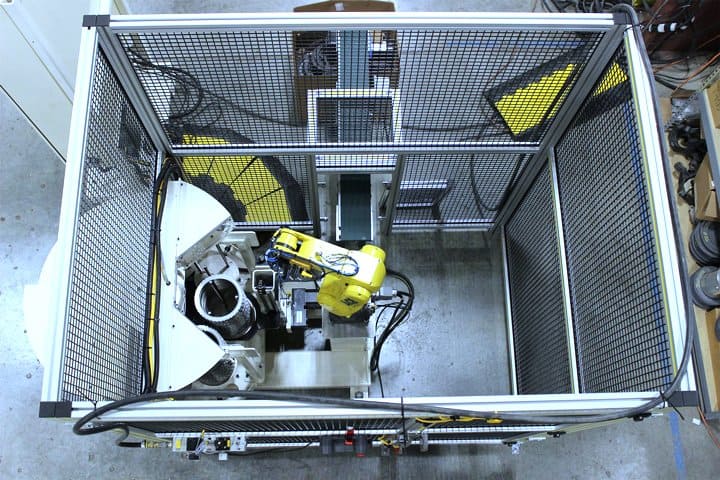 Robotic arm performing precise assembly inside a safety enclosure.