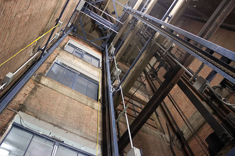 Modern building exterior with glass elevator and brick walls.