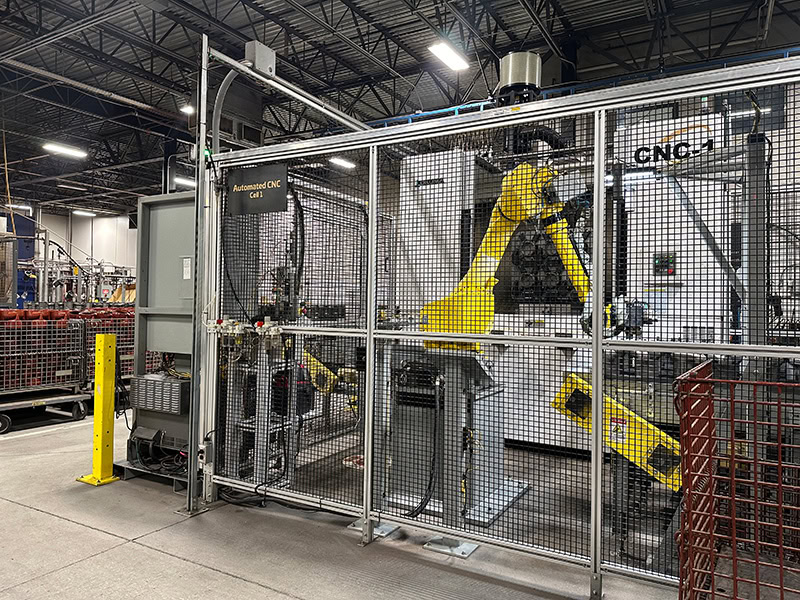 Automated CNC robotic system enclosed in safety fencing at Adaptec Solutions.