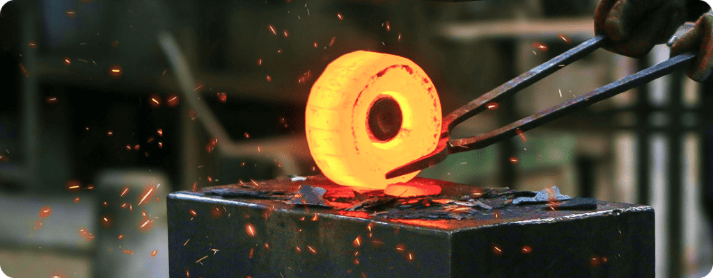 Hot metal forging process in manufacturing with glowing metal and sparks.