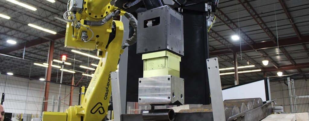 Industrial robotic arm operating metal forming machinery in factory.