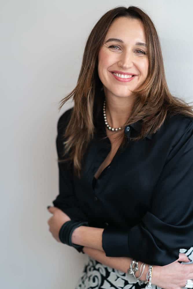 Professional headshot of Maria Rolles, founder of Ads Couture, smiling in a black blouse.