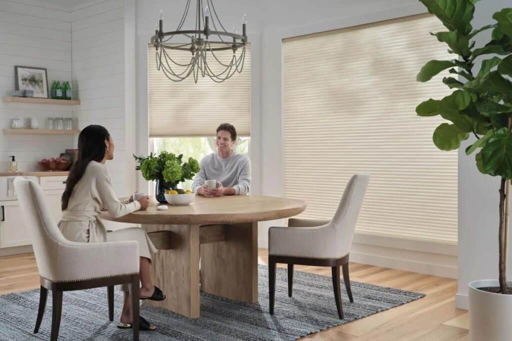 Cozy breakfast nook with large window blinds and fresh greenery in a modern dining space.