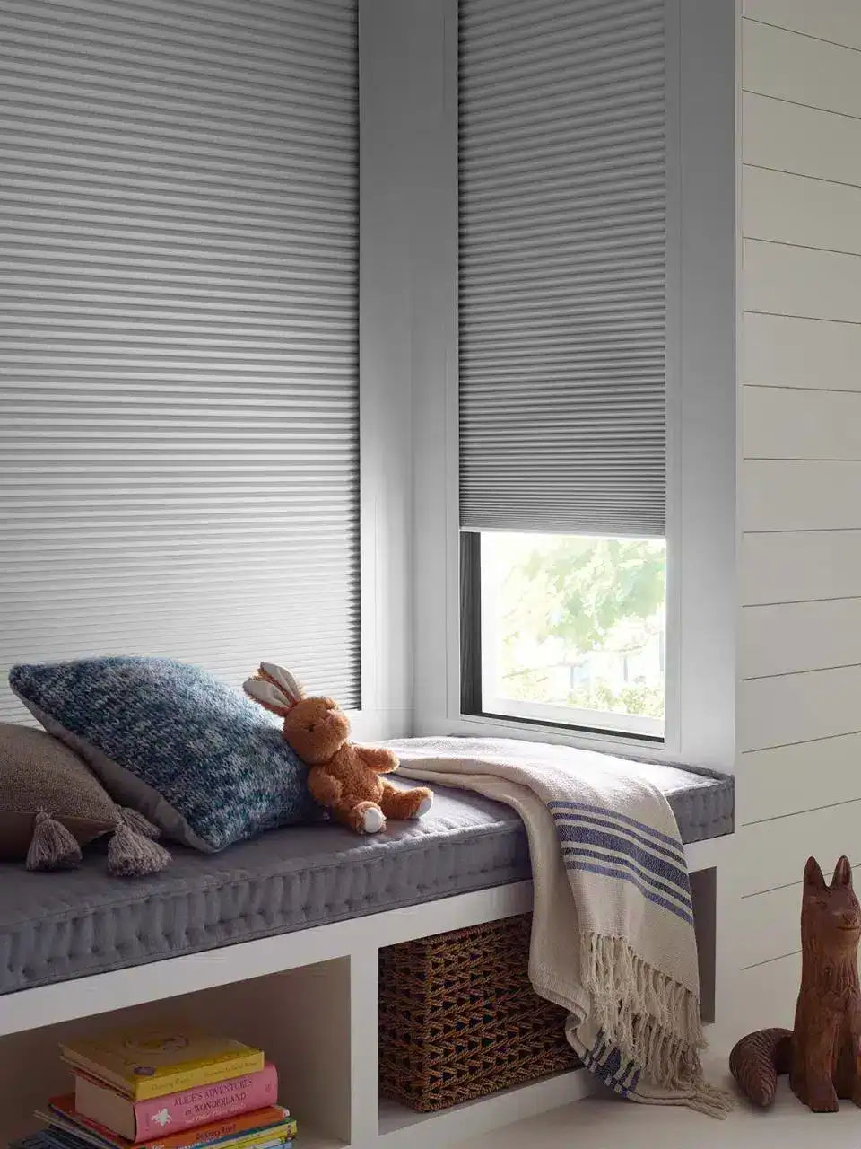 Smooth gray window blinds with a cozy window seat for relaxing and reading, enhancing home comfort and style with expert custom window treatments.