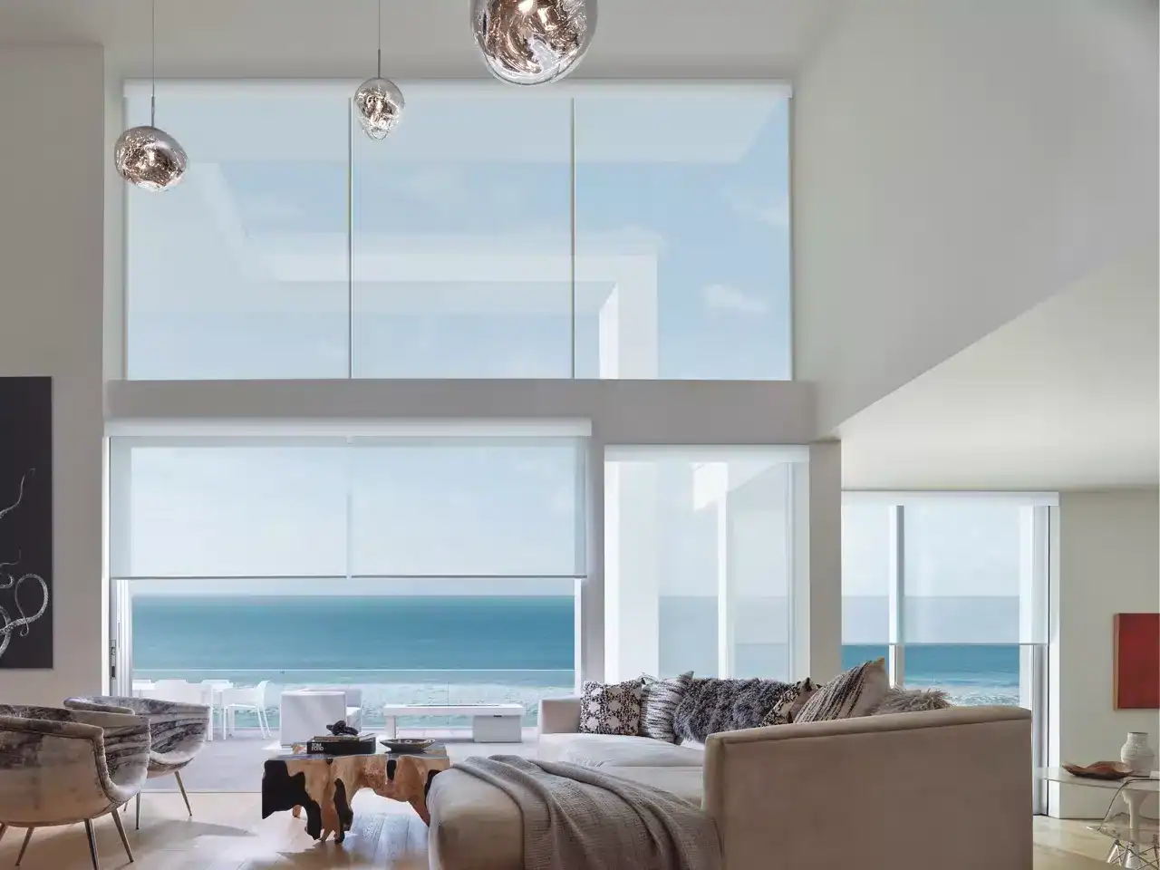 Bright living room with large ocean view windows featuring modern blinds, natural light, and elegant decor from Advance Blinds & Drapery.