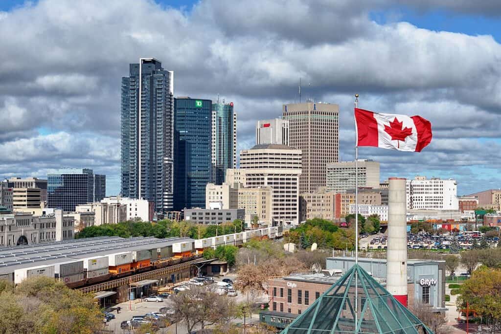 Skyscraper skyline featuring Toronto's downtown with city buildings, CN Tower, and Canadian flag fluttering in the wind, emphasizing urban landscape and Canadian pride.