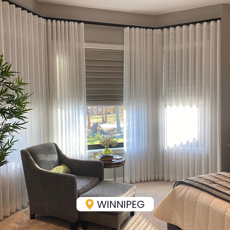 Bright living room with sheer curtains, cozy armchair, and large windows offering natural light. Ideal setting for in-home consultation, showcasing comfortable and stylish interior design.