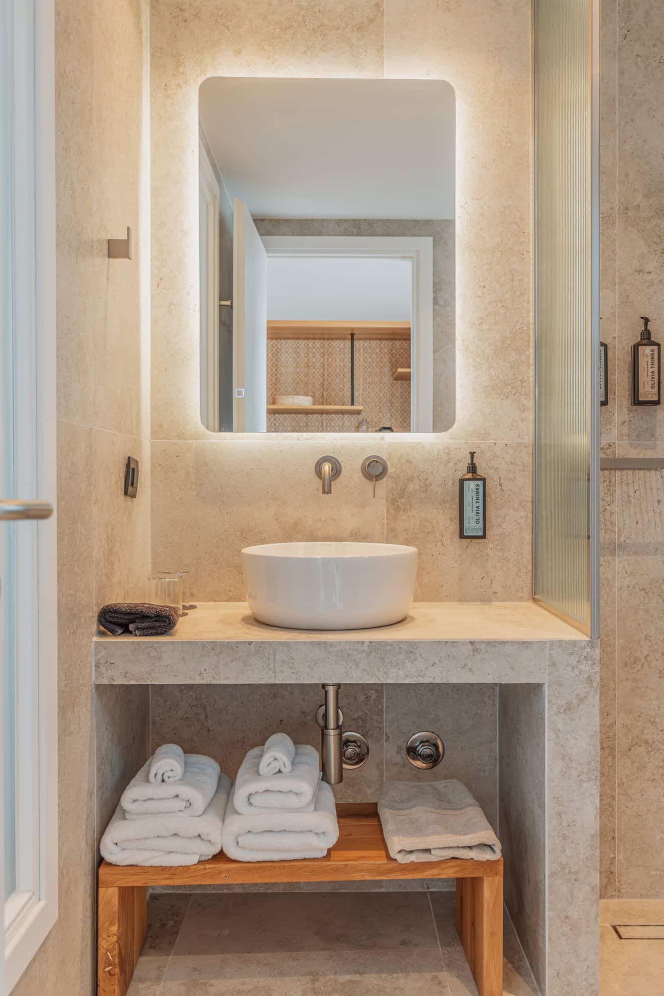 Elegant bathroom vanity with white vessel sink, soft lighting, and cozy towels.