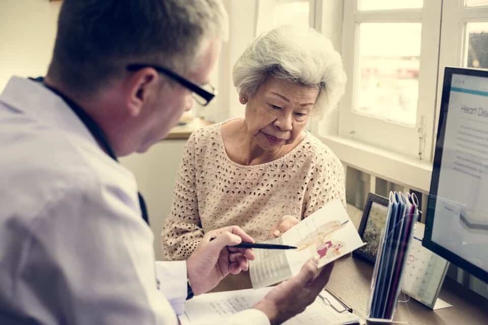 Elderly woman talking with a doctor during a Hawaii 329 medical cannabis card appointment, reviewing information together.