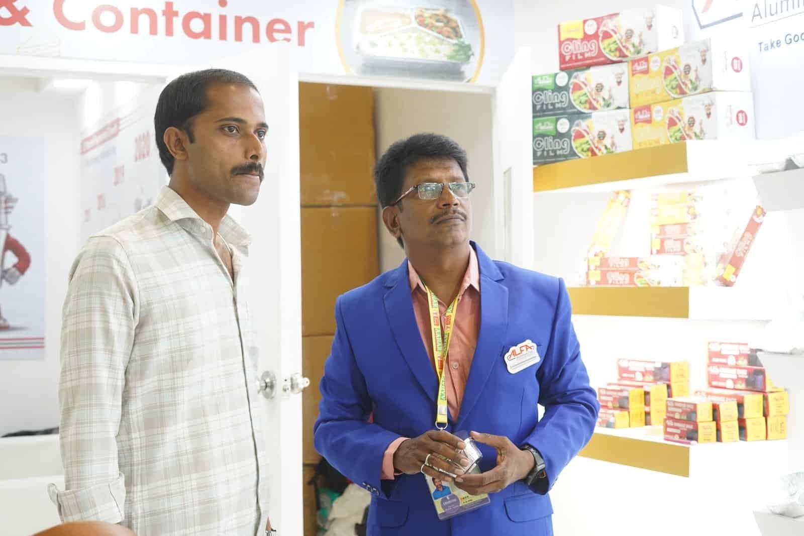 Two men examining Alfa foil containers at a retail store display.