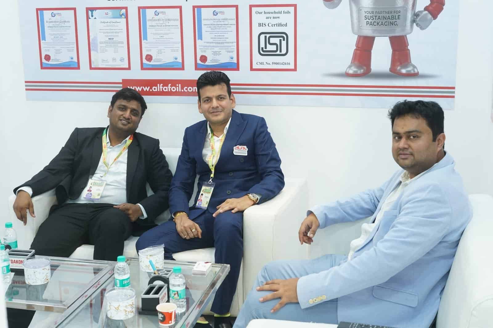 Alfa Foil Containers displayed at trade show with professionals discussing packaging solutions.