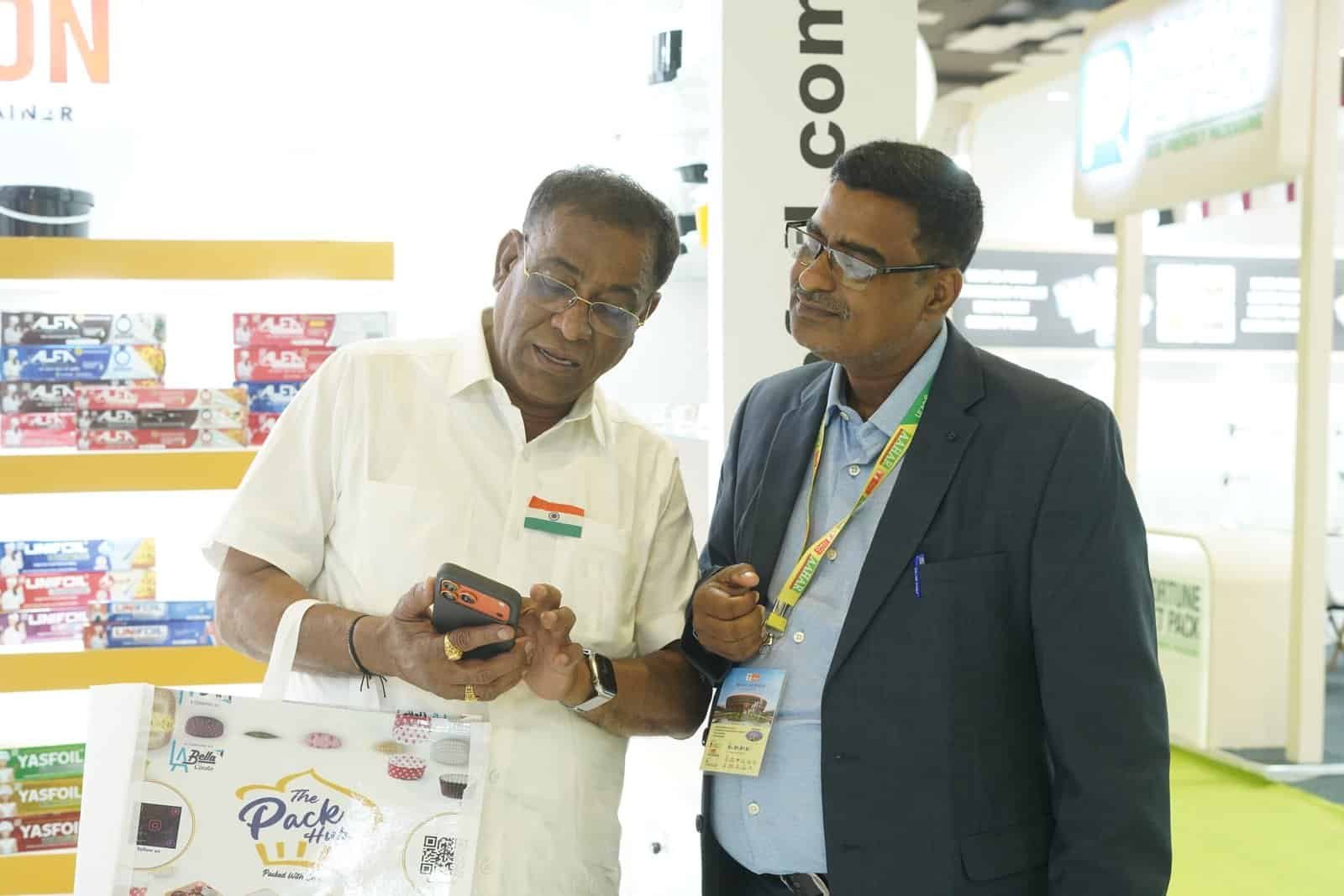 Two men discussing Alfa foil containers at a trade show.