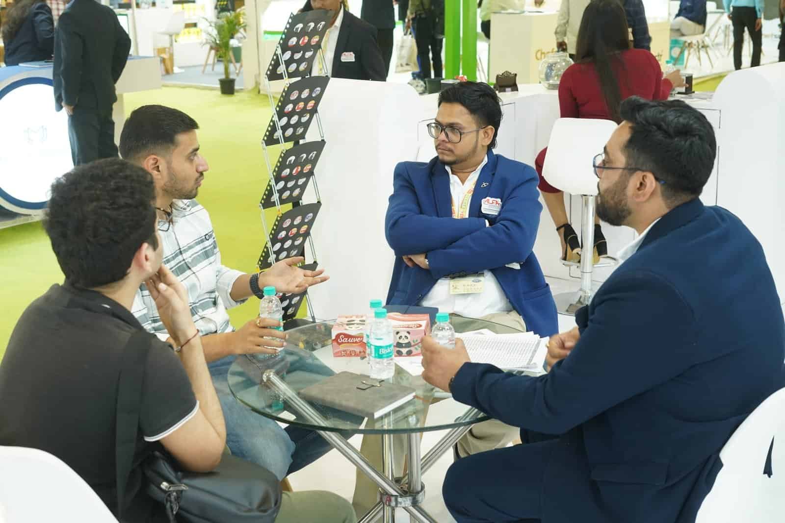Group of professionals discussing Alfa Foil containers at a trade show.