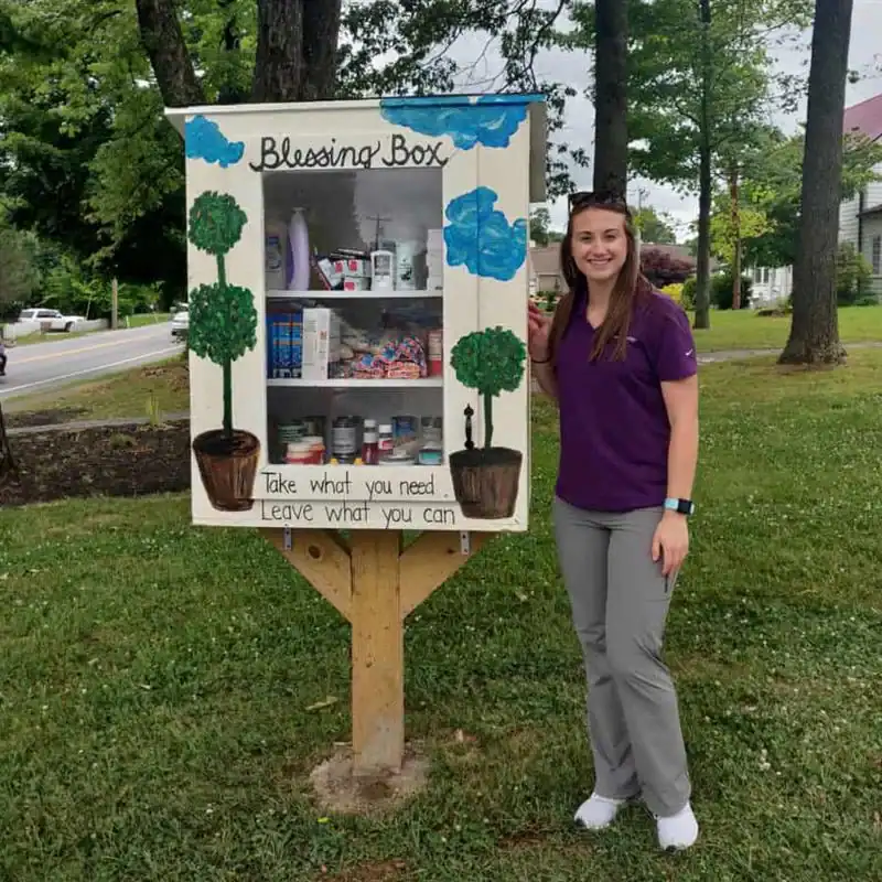 Community Blessing Box with supplies and a smiling volunteer.