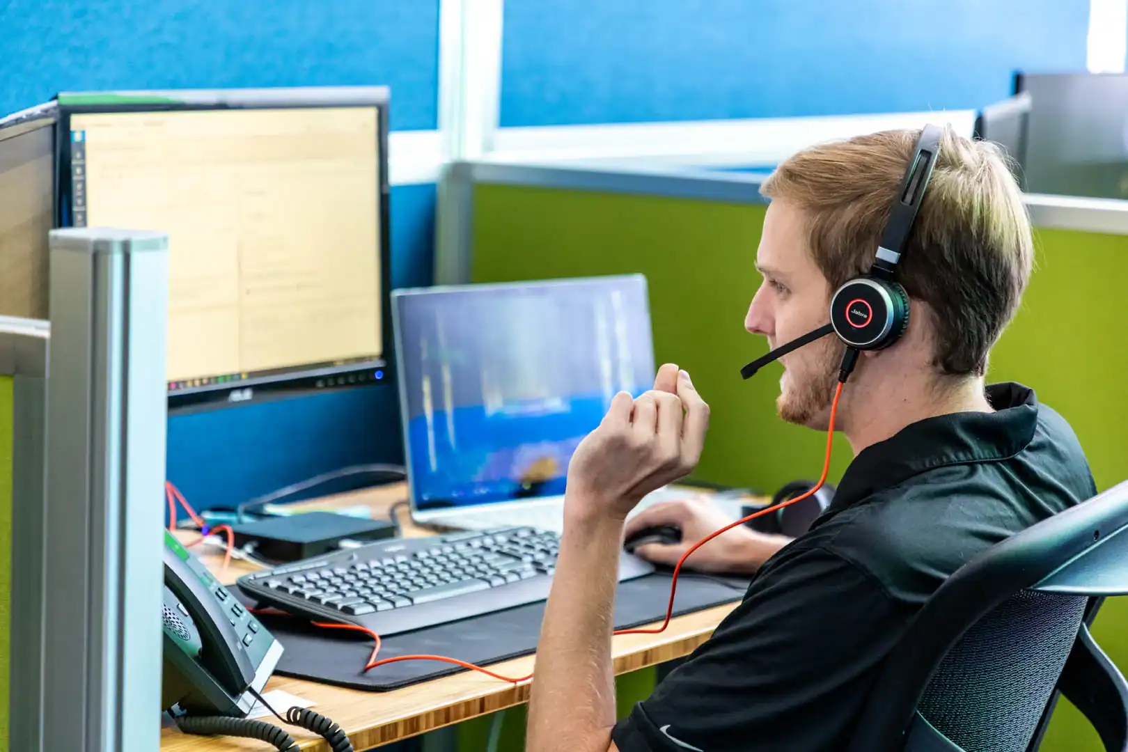 Customer support representative with headset at computer workstation.