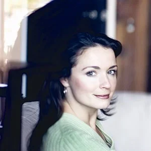 Confident woman with dark hair in a modern office environment.