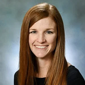 Smiling woman with long red hair in a professional setting.