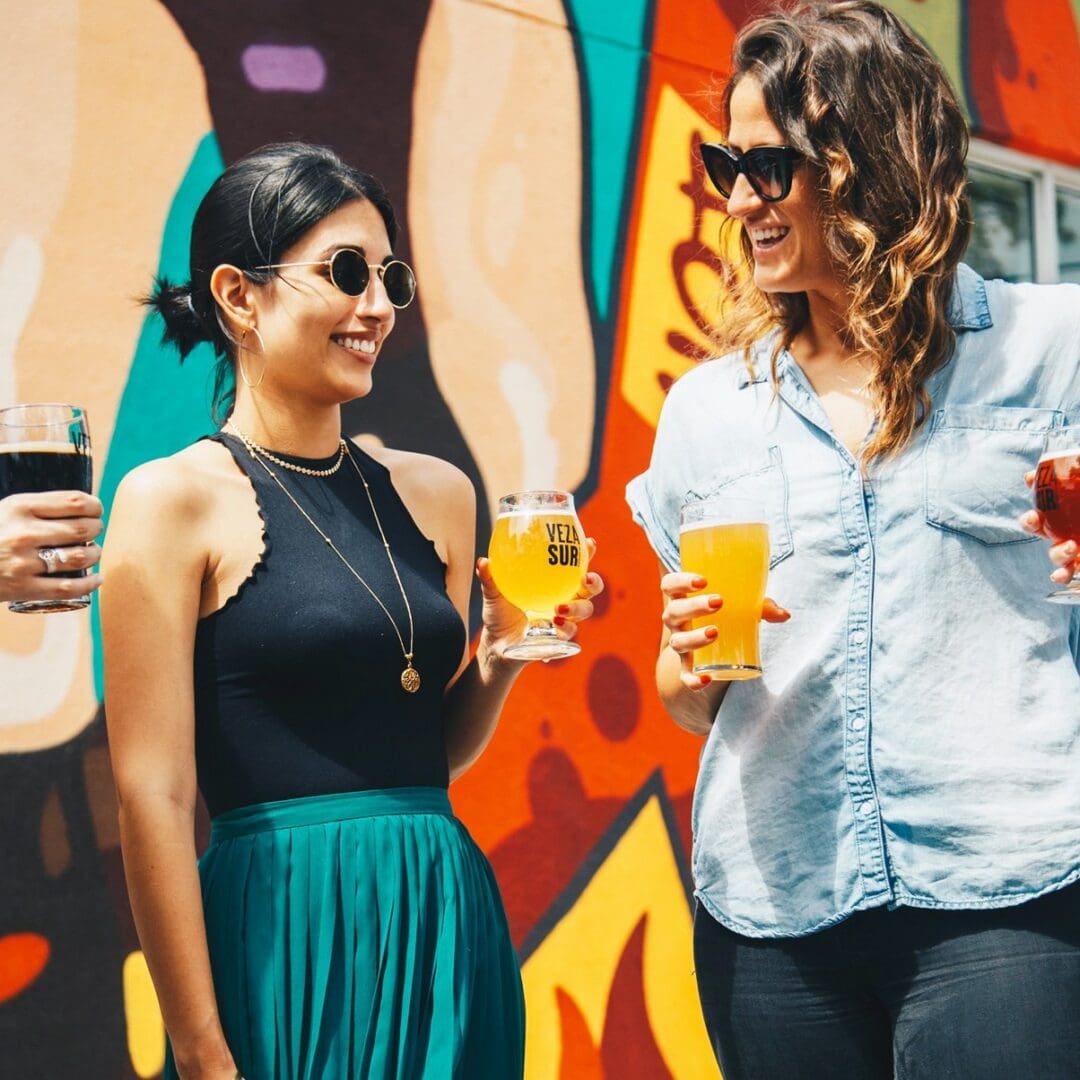 Enjoying drinks outdoors in front of a colorful mural with friends.