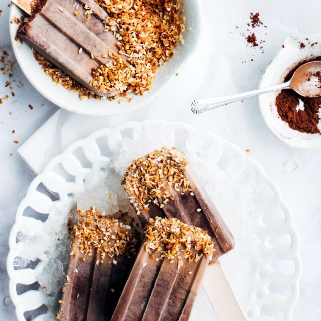 A delicious chocolate ice cream bar coated with crushed nuts on a decorative white plate.
