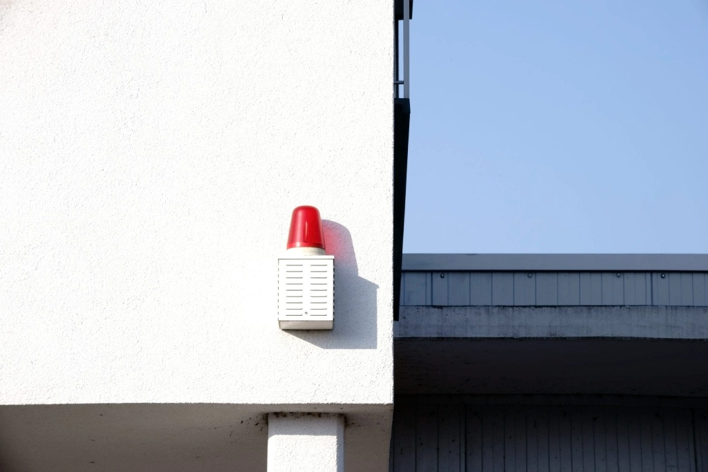 A red warning light with a speaker throws a shadow