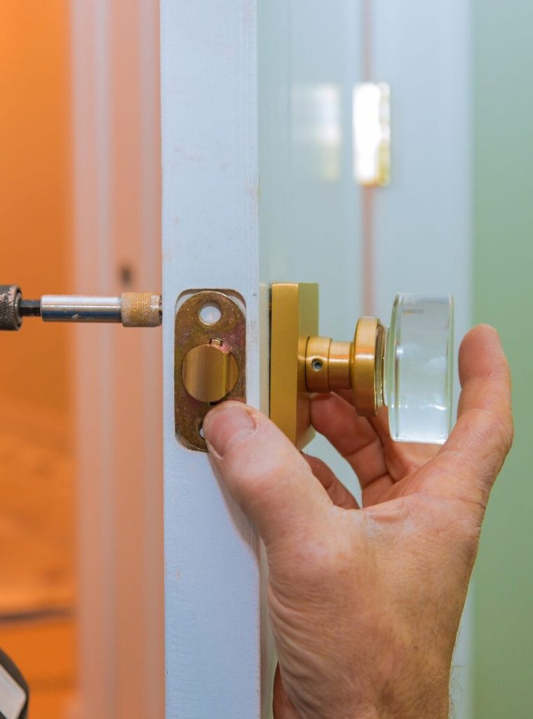 Closeup of a professional locksmith installing or new lock on a house door handle with screwdriver