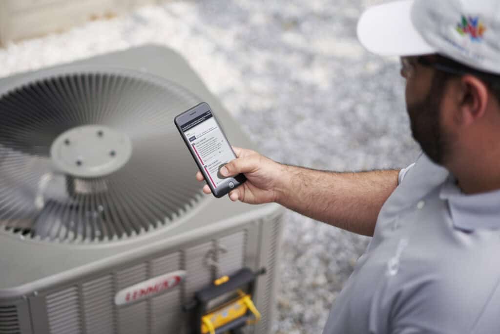 HVAC technician inspecting air conditioning unit with smartphone for diagnostics or maintenance.