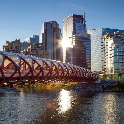 Modern cityscape with iconic bridge and high-rise buildings during sunset, showcasing urban development and architecture.