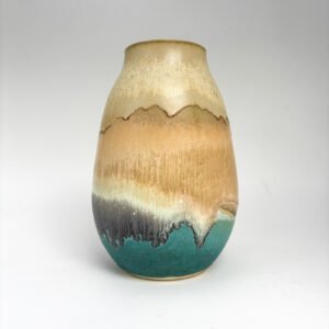 Handmade ceramic vase with flowing glaze inspired by coastal landscapes. Earthy tones transition from golden sand to charcoal black and sea green, evoking a shoreline. Crafted by artist Amelia Johannsen.