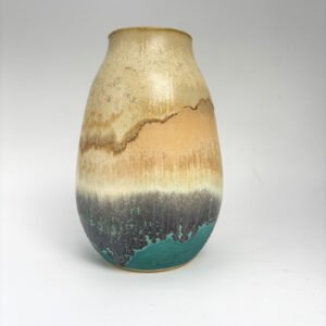 Handmade ceramic vase with flowing glaze inspired by coastal landscapes. Earthy tones transition from golden sand to charcoal black and sea green, evoking a shoreline. Crafted by artist Amelia Johannsen.