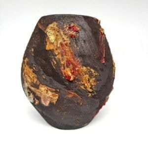 organic black ceramic vase with molten red and ochre glaze, placed on white background.