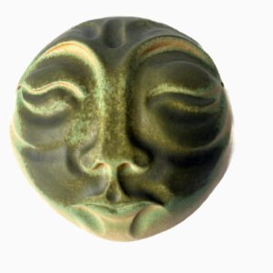 Hand-built ceramic moon wall sculpture featuring a serene face with layered green and earthy glazes.