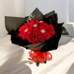 Ramillete de rosas rojas y flores decorativas en envoltorio negro y lazo rojo, estilo elegante, ideal para ocasiones especiales en Nezahualcóyotl.
