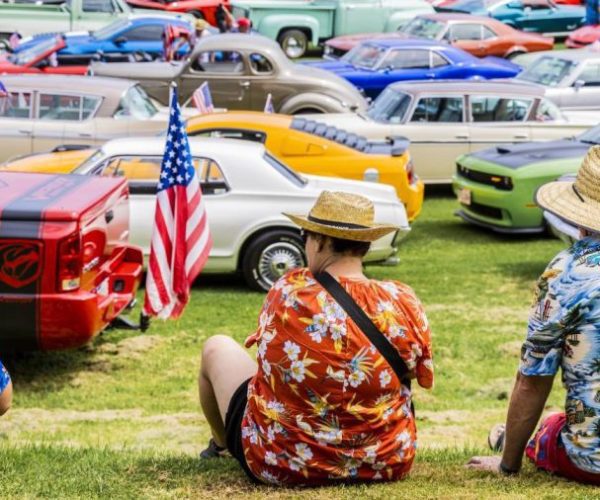 Classic American cars at Americarna event in New Zealand, vintage car show with enthusiasts frolicking, colourful automobiles park on grass.