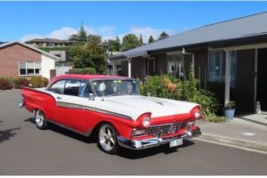 Summerset Resthome 7 Classic 1950s red and white vintage car parked on street in front of modern homes.
