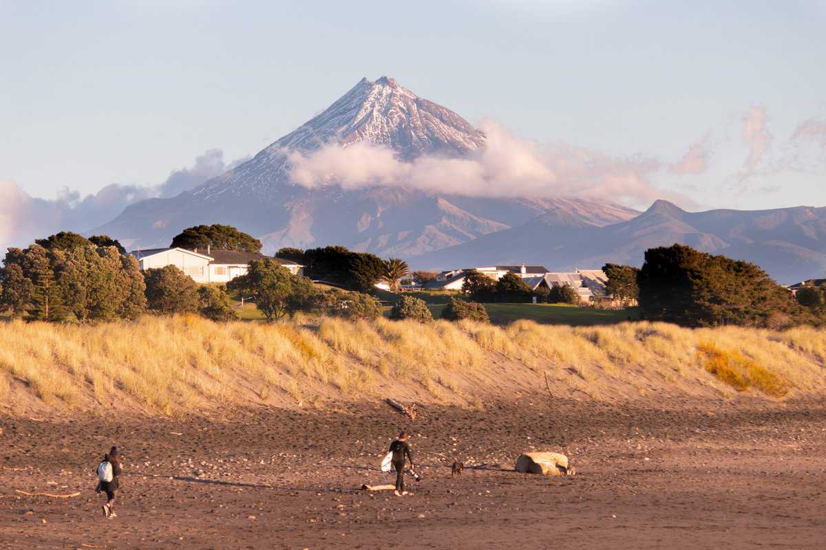 Vibrant New Zealand landscape with Mount Taranaki volcano in background.