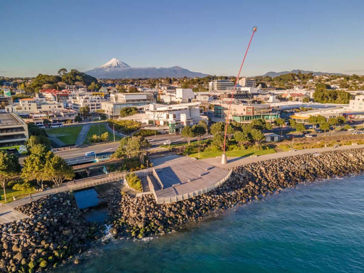 Aerial view of Napier city with Mount Taranaki in the background, showing coastal scenery, urban landscape, and vibrant downtown areas in New Zealand.