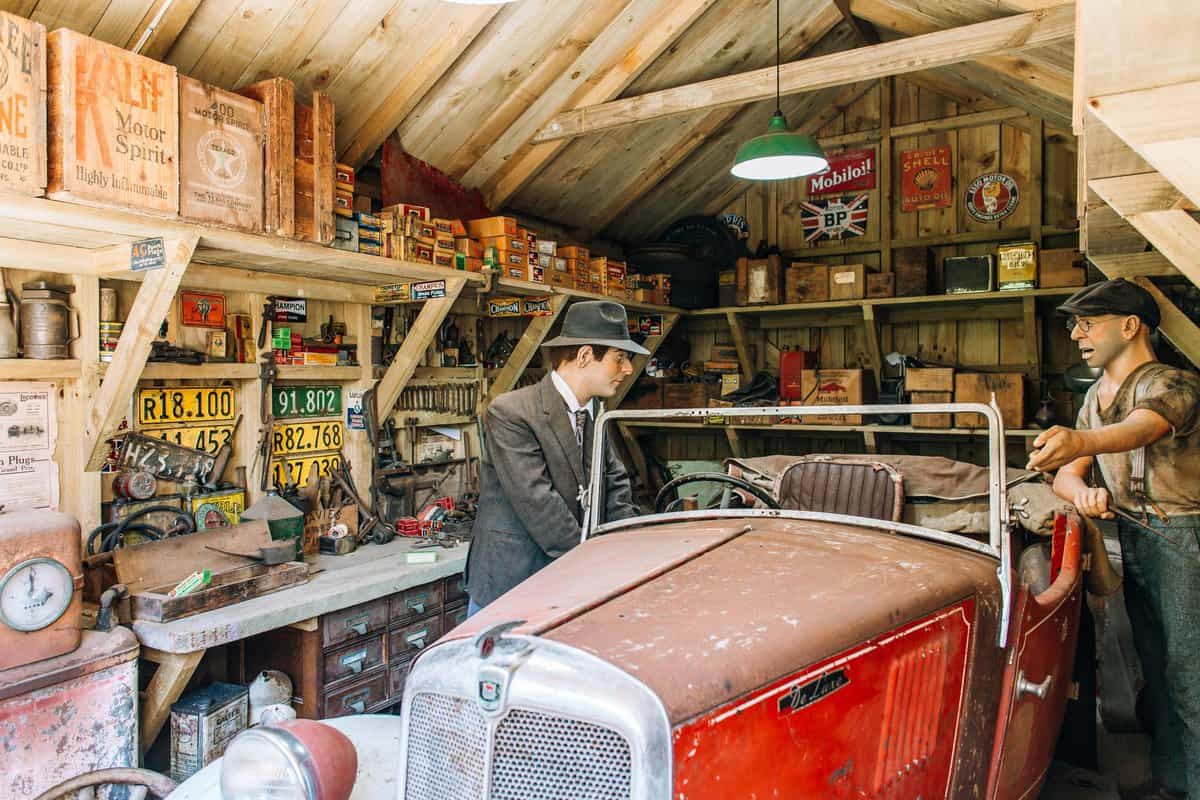 Vintage workshop with classic car and automotive memorabilia, perfect for car enthusiasts.