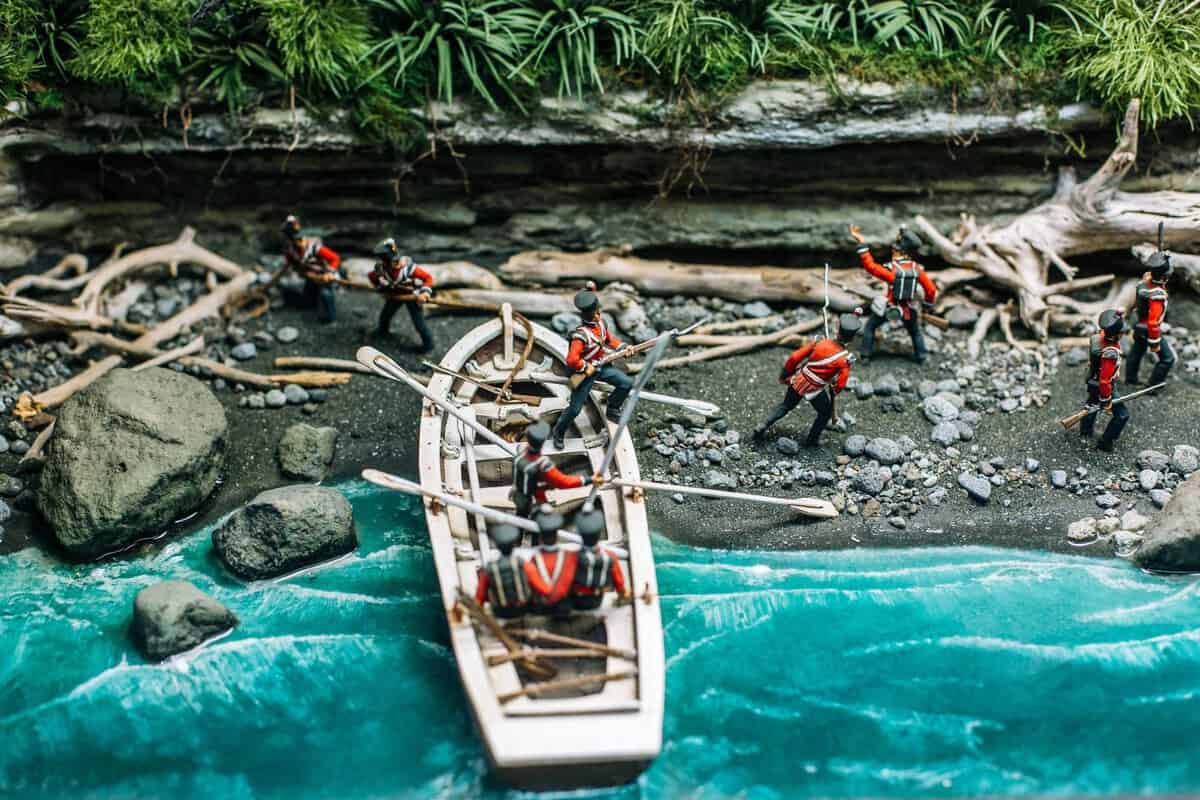 Small figurines of explorers or adventurers on a miniature river crossing scene.
