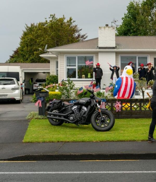 Vibrant American-themed house decoration with flags, inflatable eagle, and motorcycle for USA celebration.