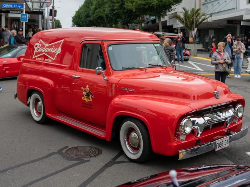 AmericarnaNewPlymouthCarnival-02873 Vintage red delivery van at Americarna car festival in New Zealand, classic American truck car show, retro vehicle showcase.