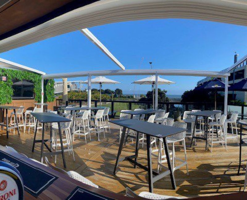 Outdoor dining area at Americarna event, featuring deck tables and seating with scenic river views.