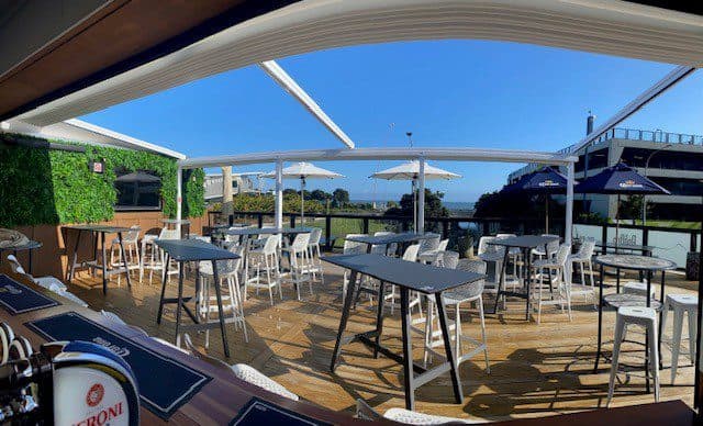Outdoor dining area at Americarna event, featuring deck tables and seating with scenic river views.