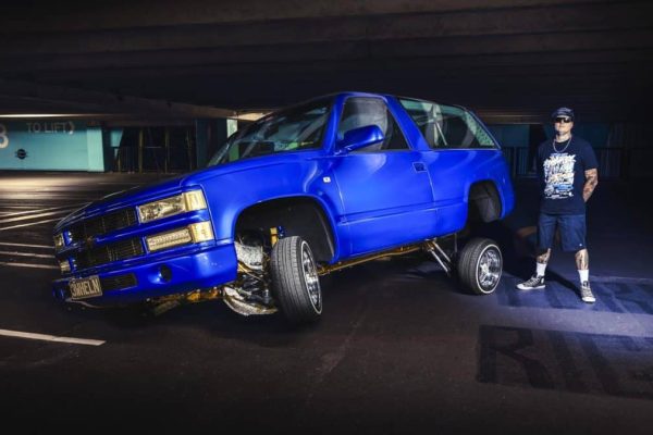 Exotic custom blue car with missing wheels in a parking garage featuring enthusiast and car culture.
