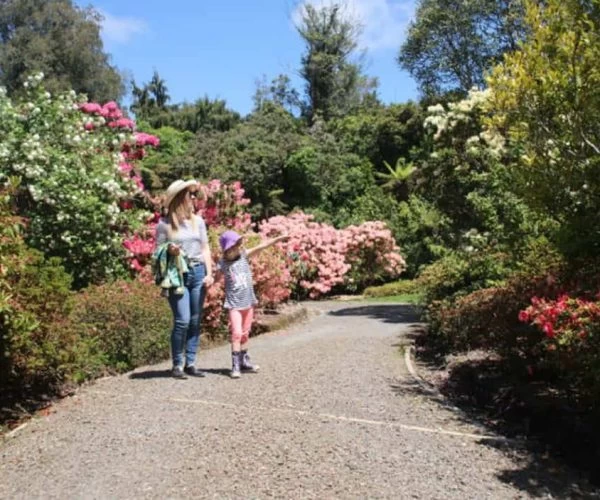 Colorful garden walk with woman and child enjoying spring blooms in Auckland, New Zealand.