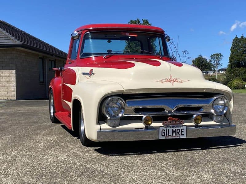 Vintage red and cream custom-built truck in a scenic outdoor setting.