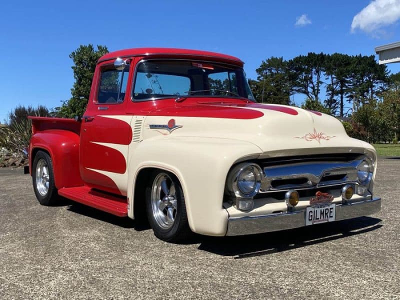 Vintage American truck with custom red and cream paint, polished chrome bumpers, and unique design features.