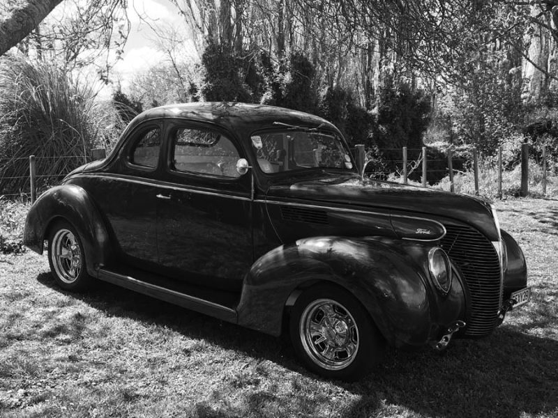 Old black Ford car displayed outdoors at Americarna car event in New Zealand.